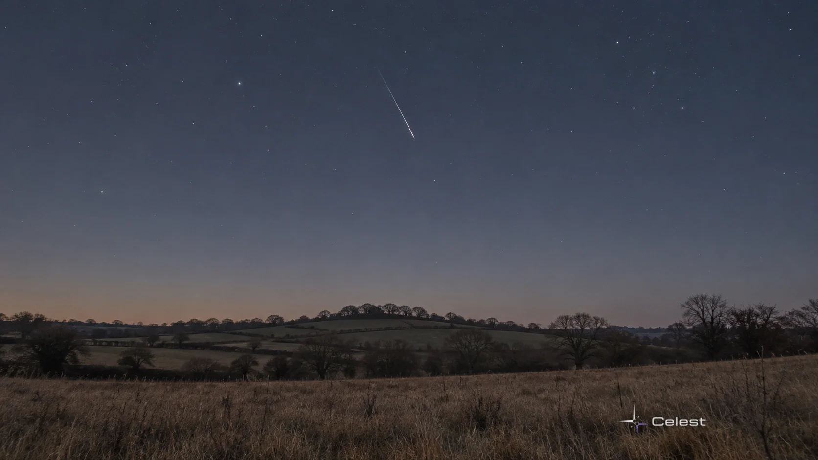 Un singur meteor discret deasupra unui deal jos, într-o seară de toamnă, sub un cer cu nuanțe naturale.