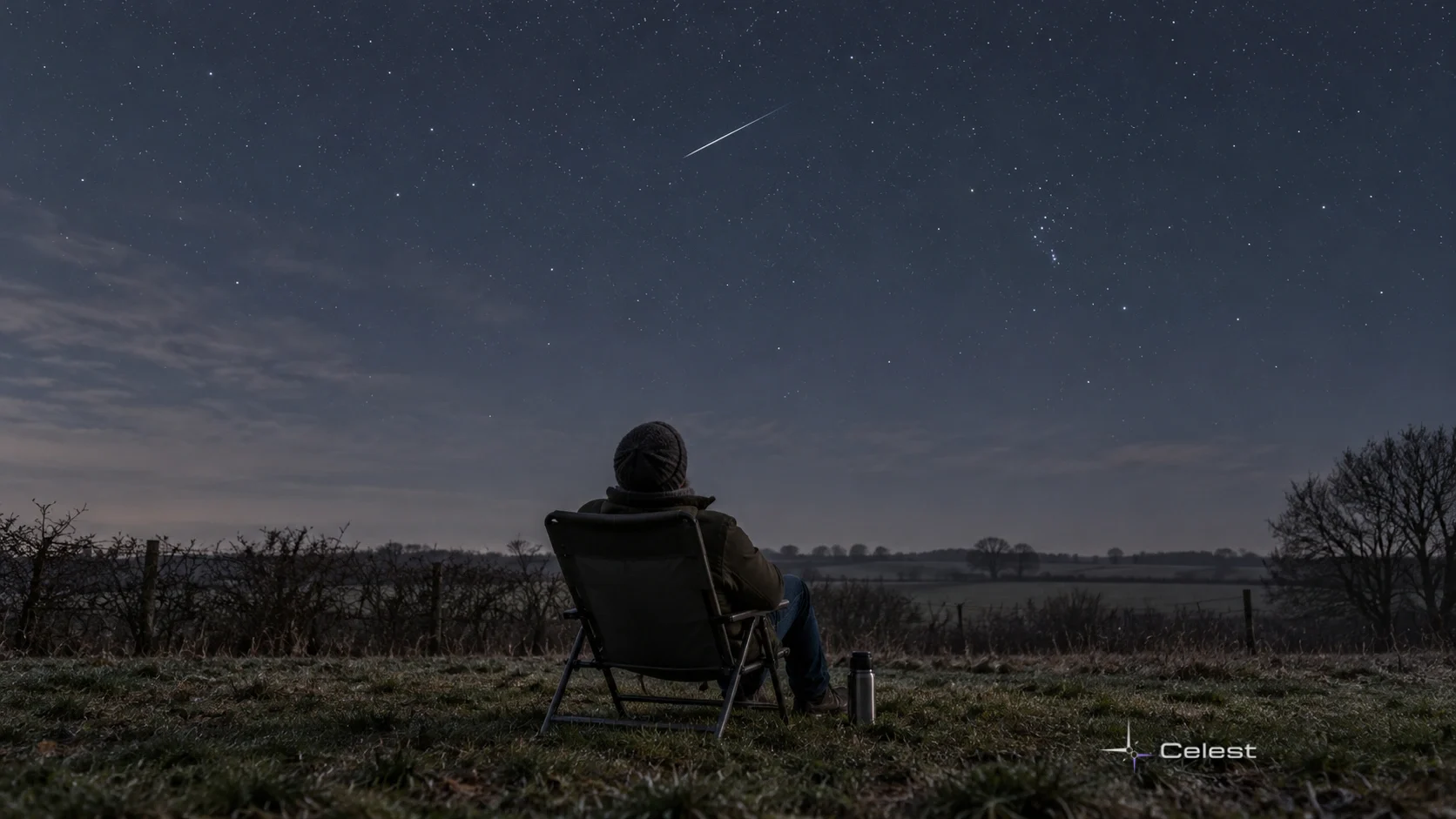 Un observator îmbrăcat pentru frig privește un meteor subțire pe cer, deasupra unui peisaj rural de toamnă târzie.